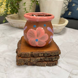 Ceramic rose gold clay 7oz clay tacita with floral design on top of 3 wooden coasters.